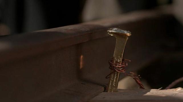 A close-up of a golden railway spike