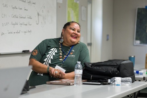 Linnea Jackson, wearing a green Acorn Wireless t-shirt, smiles while seated a table during a recent Tribal Broadband Bootcamp