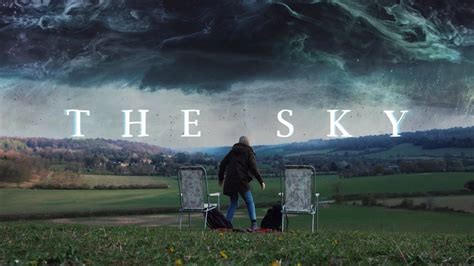 Image of a pastoral landscape and a scary looking sky with lots of colors, and a woman surrounded by lawn chairs looking up.