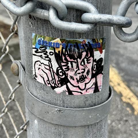 A slap sticker spotted on the street. It has as stylized drawing of a woman smoking a cigarette. She looks buff and kind of mean. 

The art is drawn on a sticker label that is mostly white, but has "Sickid's Raspados" printed on the top.