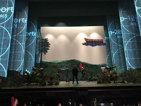 Stage hands checking out trees and plants moving across the stage as projections are tested on the sides