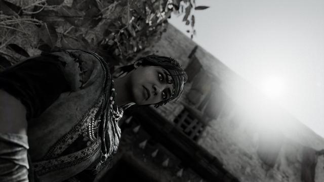 Nehal leaning against a wall with the sun shining above. In black and white.