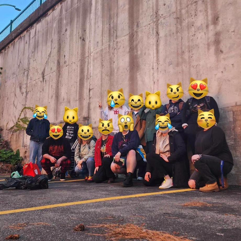 A group of warm up volunteers standing and crouching in front of a wall.