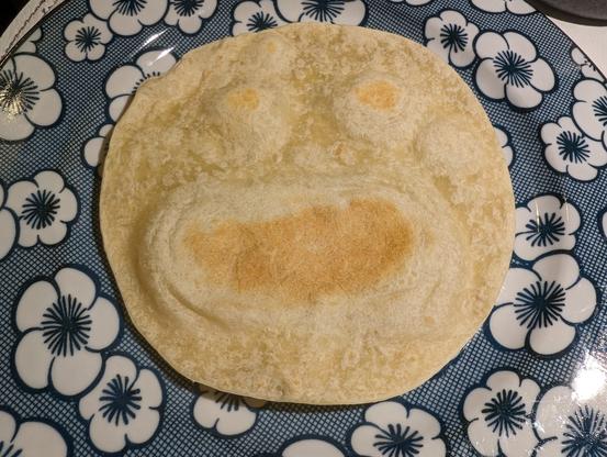 toasted flour tortilla with dark spots that resemble a screaming face