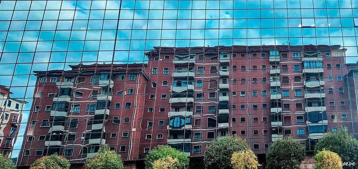 fachada de un edificio reflejada en la de otro.