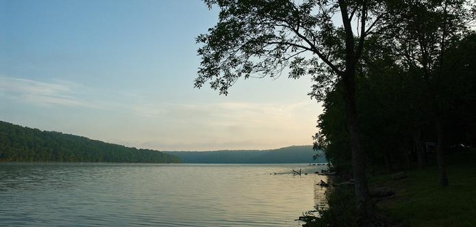 Public Domain Photo, Missouri State Parks, Lake Ozarks, flickr. A serene lake surrounded by banks of trees. Near clear skies.