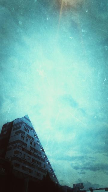 a weird triangular residential building and sky with some clouds
