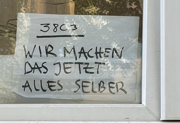 Ein weißes Blatt DIN A4 Papier klebt am unteren Rand eines Fensters im Erdgeschoss. Darauf steht mit dickem, schwarzem Edding geschrieben:

38C3
WIR MACHEN
DAS JETZT
ALLES SELBER

Ob das wirklich mit dem 38C3 zusammenhängt ist völlig unklar.