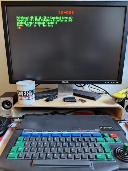 Photo of an Enterprise 64 microcomputer running PolyPascal. Enterprise coffee mug and multiple computer chips visible.
