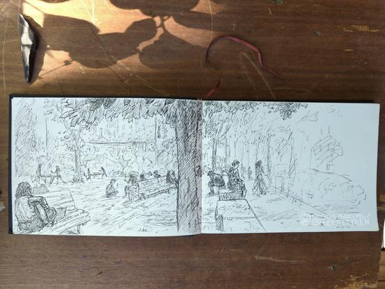 Black Fineliner on paper.

Cityscape.  On the left, an open space with benches, table tennis tables and various people sitting around or playing table tennis. On the left on the bench is a person playing the guitar. In the background, graffiti-painted house walls with bushes and trees in front of them. In the middle of the picture, a tree trunk in the foreground, with a canopy of leaves at the top. On the right is a wall separating the open space from the sidewalk and street. People are sitting on the wall. People are walking on the sidewalk. Trees and cars are indicated on the right.

Translated with DeepL.com (free version)