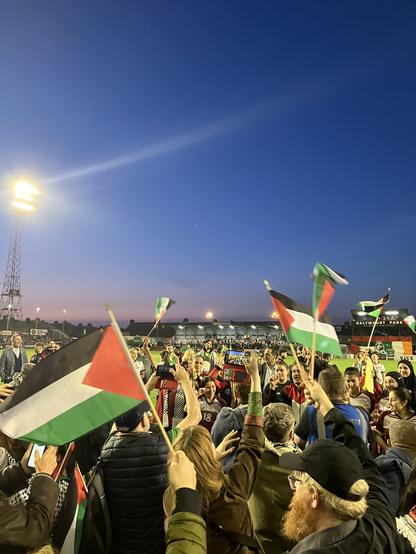 A photo taken pitch-side at Dalymount Stadium, of a crowd celebrating beside members of the Palestine national women's team and Bohemian FC women's team, Dublin, 15 May 2024. (Photo by me.)