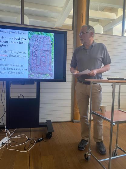 Photo of Henrik Williams presenting about the rune carver Torkel.