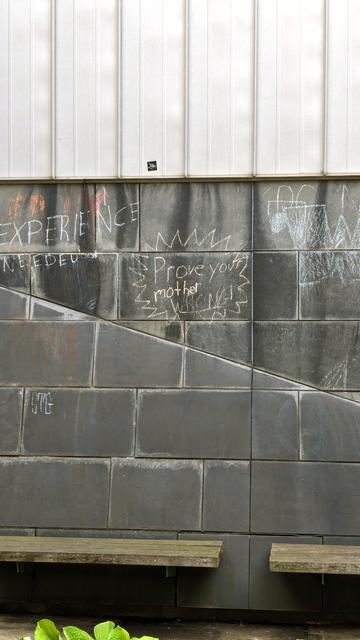 Wall made of large grey stone or concrete blocks, chalk writing saying "prove your mother wrong"