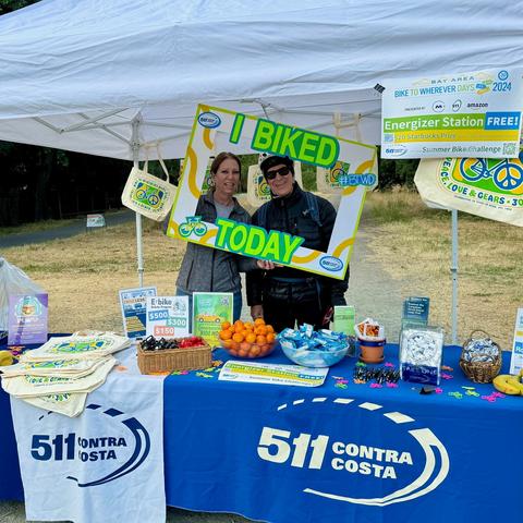 Photo of two people standing at the 511 Contra Costa Energizer Station holding up an oversized I Biked to Work photo frame which makes them look like they're inside the frame for this picture.
