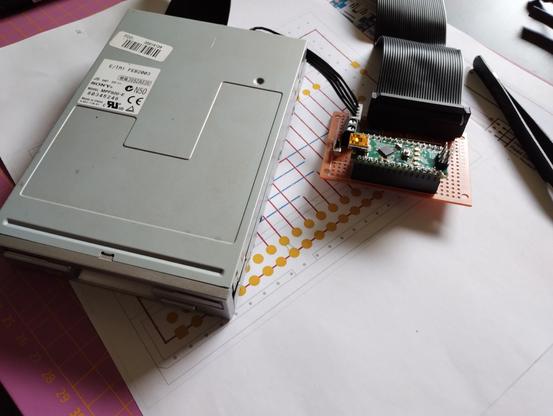 the board with plugged in Arduino Nano, and a floppy drive connected by a ribbon cable and power cable