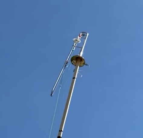 A trombone mounted on a vertical pole with a pulley connected to the slide.