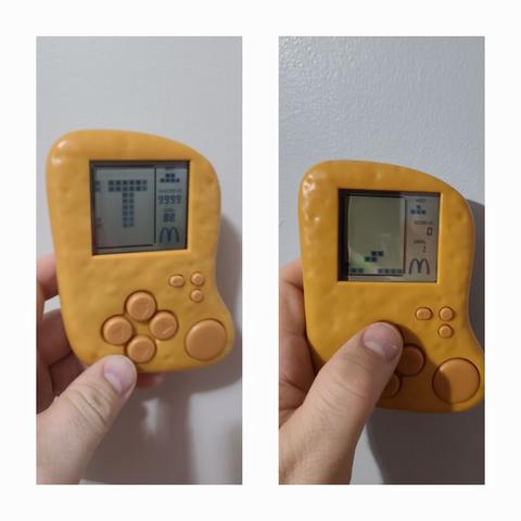 Collage of two photographs stacked vertically with a thick, white border around everything. Both photographs show a plastic framed Chicken McNugget toy with an LCD screen and buttons on it in a white person's hand. The screens are on in both cases. The image on the left shows a "T" in the center with the McDonald's logo in the corner and a level of 88 with a score of 9999. The image on the right shows a z-shaped block falling with a score of zero on Level 1 with the same McDonald's logo in the corner.