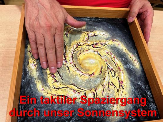 Das Bild zeigt ein Tastmodell einer Galaxie und eine menschliche Hand, die das Modell berührt.
Diese Modelle können beim Aktionstag live erlebt und erfühlt werden.