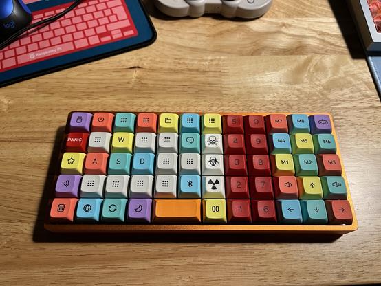 A customized mechanical keyboard with colorful keycaps featuring various symbols and icons, placed on a wooden desk.