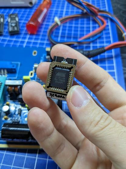 EEPROM adapter held in my hand. It is a 24 pin device, with a PLCC socket soldered on top and an AT28C64 inserted in the socket