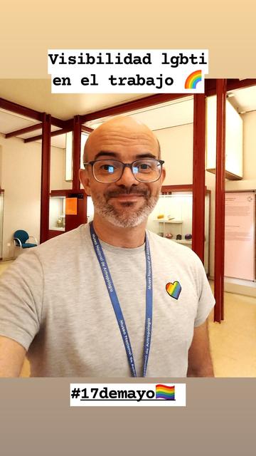 Barbudo con camiseta y colgante azul en habitación de vigas rojas