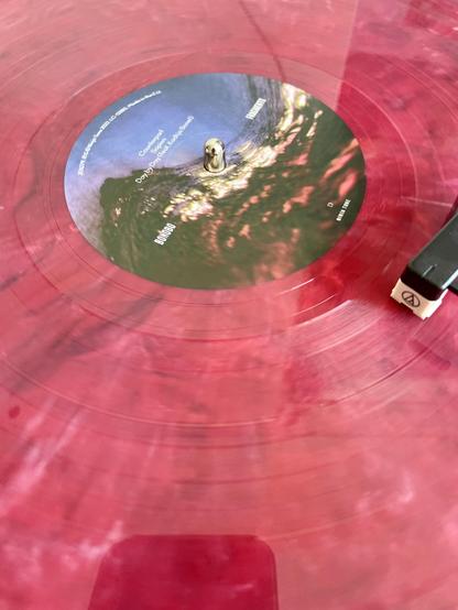 Centre shot of red-marbled record being played.