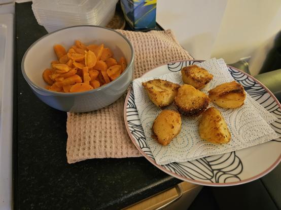 A photo of two dishes; a fan of perfectly roasted potatoes and spicy, piped carrots.