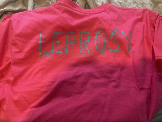 Back of dark pink band tee that reads “leprosy.”