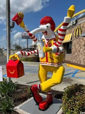 A Weevio dress like Ronald McDonald with fries in the top right hand a happy meal in the lower right hand and a drink in the lower left hand