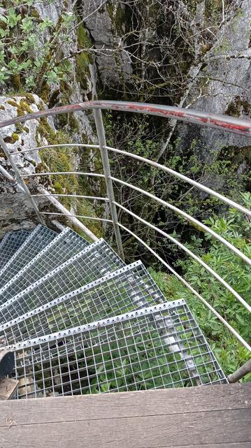 Dans le sens de la descente, escalier tournant en grille caillebotis.
En contrebas, l'à pic d'une falaise et de la végétation.