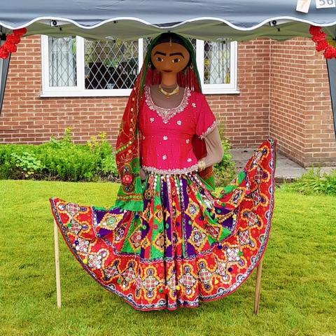 A Bollywood dancer scarecrow, dressed in a brightly coloured dress of reds and greens.