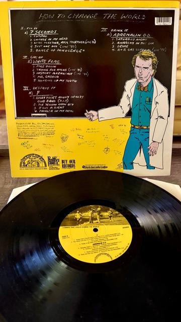 Back cover art shows the same character, now in a lab coat and standing in front of a black board with the track listings spelled out. 

Black vinyl disc with yellow label below