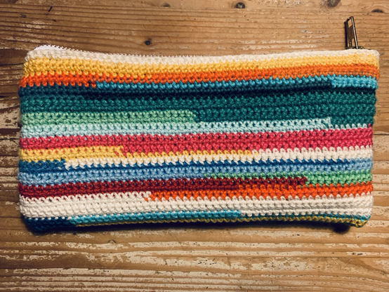 Gehaakt etui met rits. Gehaakt met heel veel verschillende kleuren in horizontale strepen van verschillende diktes en lengtes