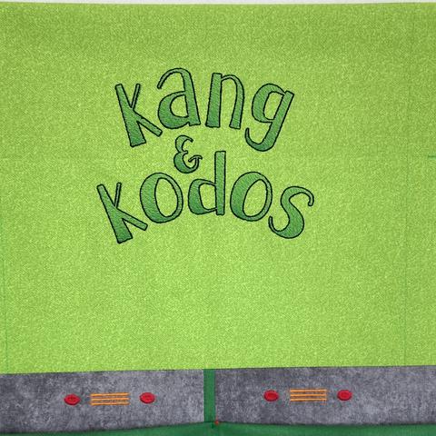 Green minimalist quilt block on a design wall; the block has the names Kang & Kodos in a fun green ombrΓ© font with a gray section below that resembles the alienβs collars