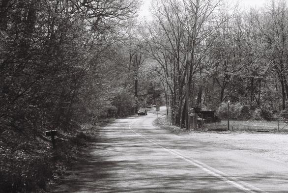 Black and white photograph of a road bending and going uphill.
