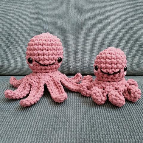 Two crochet octopuses with cute stiched faces on a sofa.