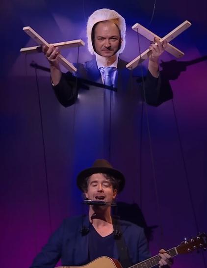 Screenshot van "Even tot hier" uitzending zaterdag 18 mei met Jeroen Woe als Wilders die aan de touwtjes van marionet Niels van der Laan als Plassterk trekt.