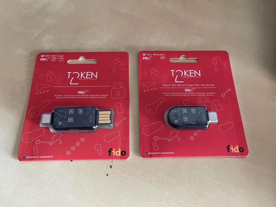 Two packaged Token2 security keys on a beige surface.