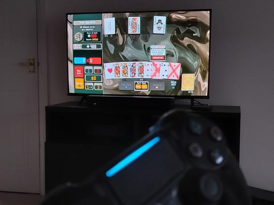 Steam deck running Balatro on the TV. A playstation 4 controller is in front, but out of focus.