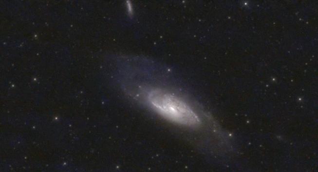 Messier 106, a bright galaxy in the Northern constellation of Canes Venatici. It is characterized by a bright detailed core and very faint outer disk. Two small galaxies are also in the view.