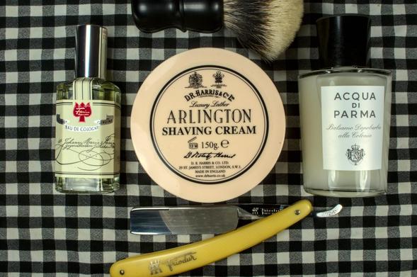 A tub of DRH Arlington cream between a bottle of AdP Colonia post shave balm and a bottle of Farina 1709 frag with a Dogclaration Mystery B16 brush and a Friodur 72-V wedge