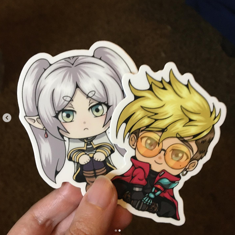 Holding a Frieren and Vash sticker