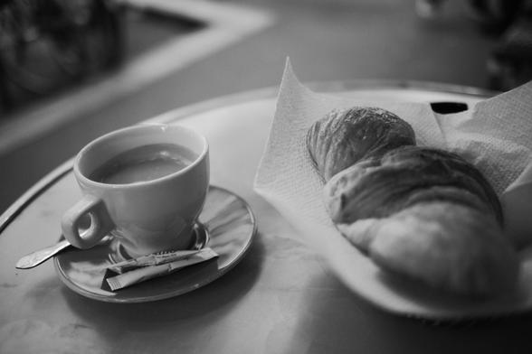 Photo Noir et Blanc d'un café et d'un croissant sur une table de café.