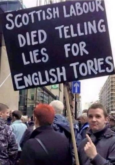 A protestor holding a placard which reads "Scottish Labour died telling lies for English tories"
