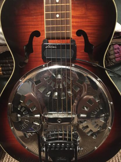 Cherry sunburst dobro guitar with silver “pie plate” and black pickup mounted just above the plate.