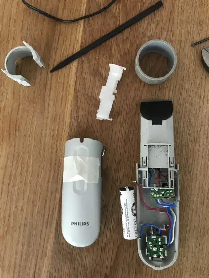Farbfoto: Die Ausgangslage … ein zerlegter Phillips Bartschneider. Dünnes Plastik und eine lächerlich einfache Elektronik werden sichtbar. Das ist kaum noch stabil wieder zusammen zu bauen.