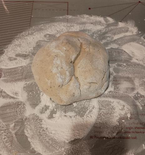 A ball of pizza dough sits on a flour covered mat. It is pizza night!