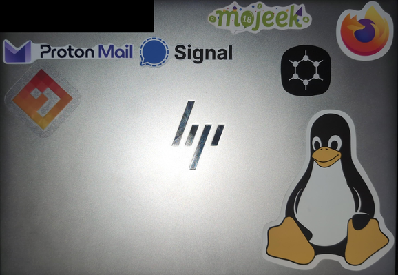laptop lid with stickers from Proton Mail, Signal messenger, Mojeek searchengine, Firefox browser, GrapheneOS, Tux (Linux), and AsteroidOS.