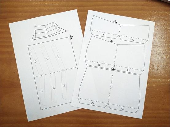 Dos folios con las piezas impresas sobre una mesa de madera.