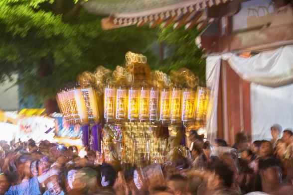 One of the last Mikoshis at Sensō-ji still being carried around the temple grounds during Sanja Matsuri, frozen briefly from a flash of light, a contrast of the frozen faces against the blur of motion.